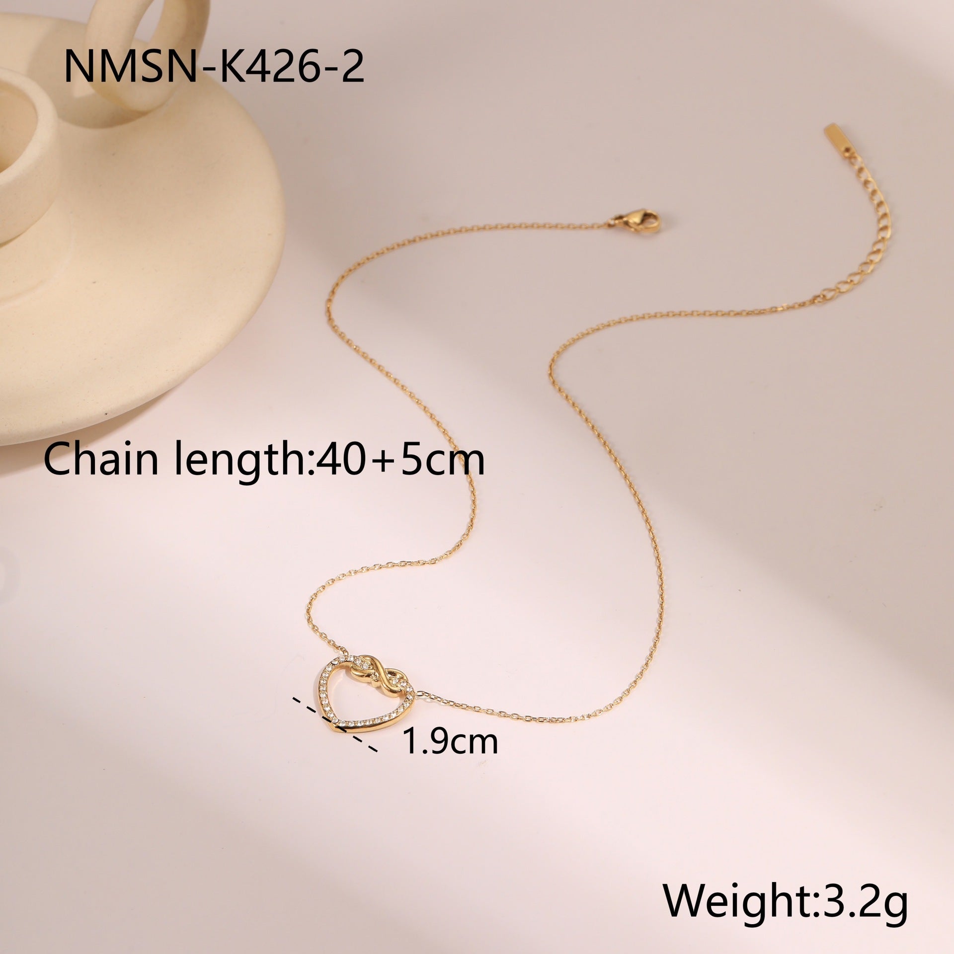 Gold necklace with heart pendant on a beige background, showing chain length and weight details.