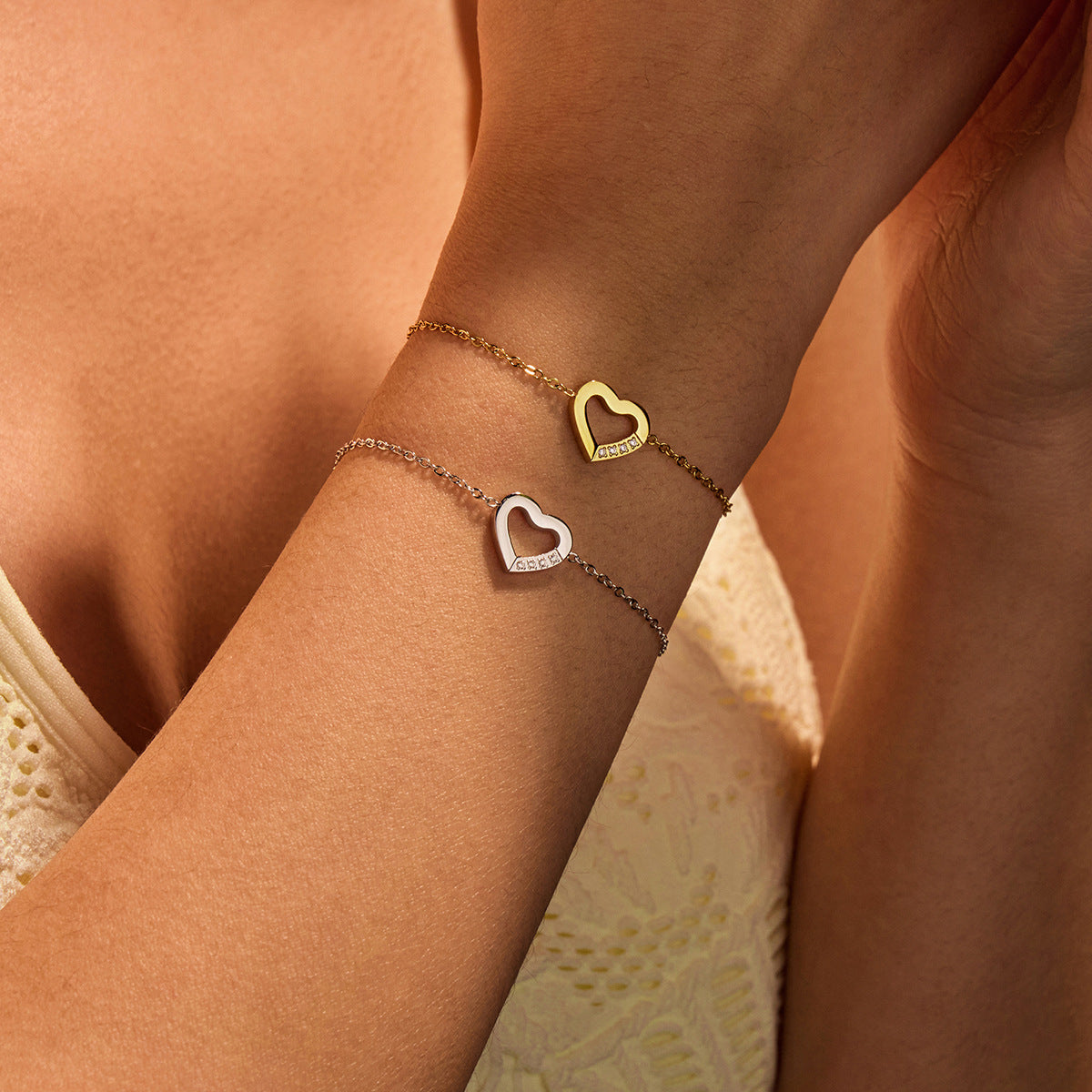 Close-up of a person's wrist wearing two heart-shaped bracelets on a neutral background