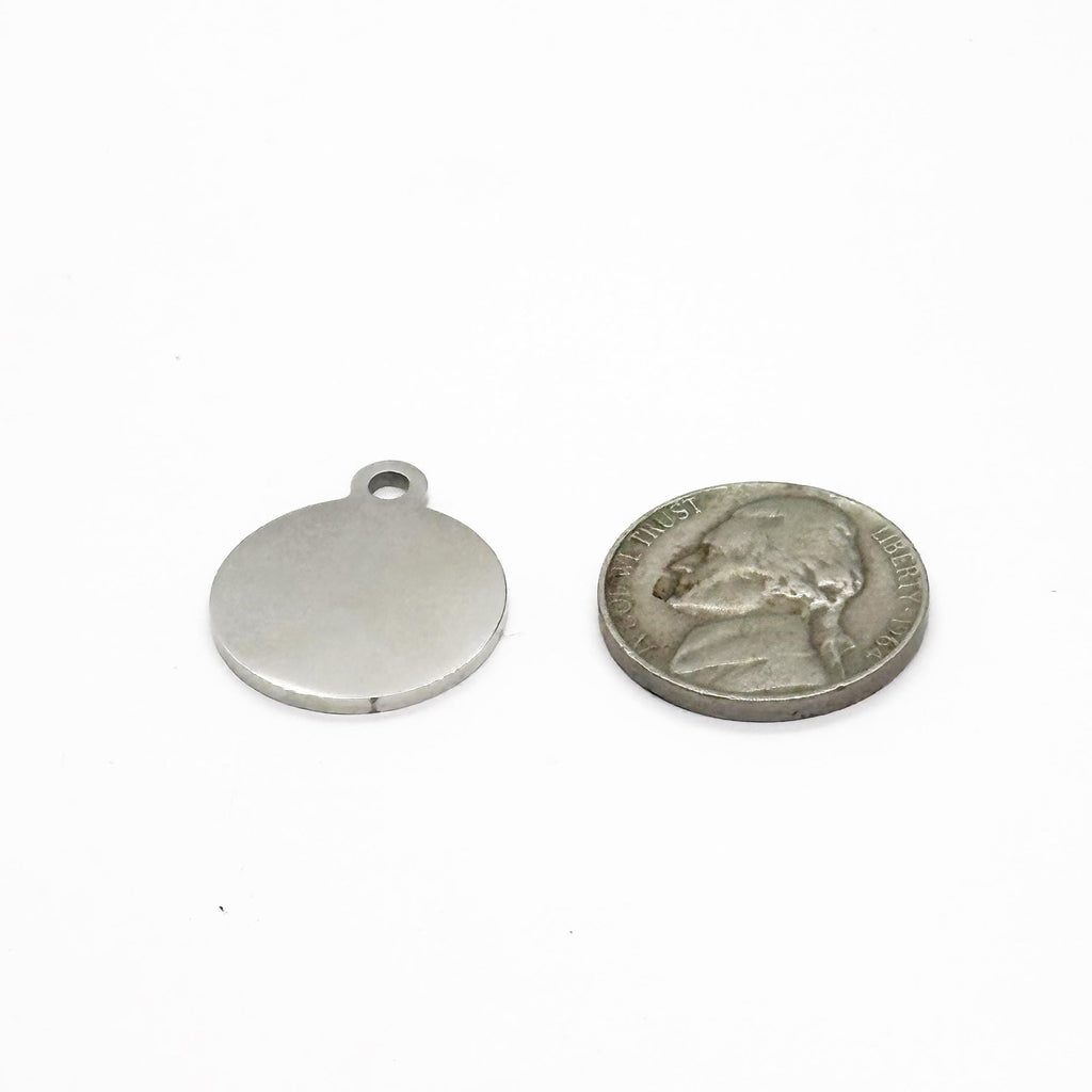 Silver round pendant next to a U.S. quarter on a white background