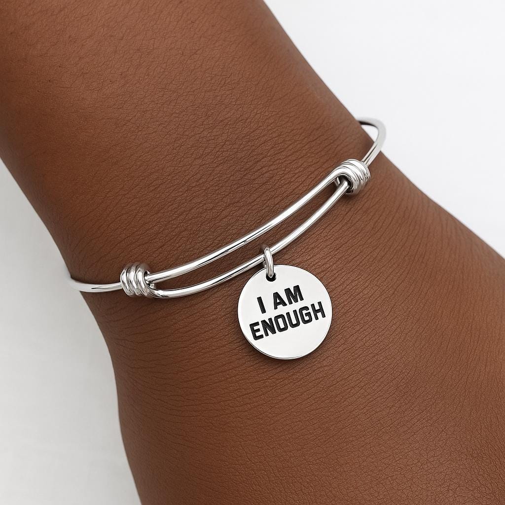 Silver bracelet with 'I AM ENOUGH' charm on a wrist